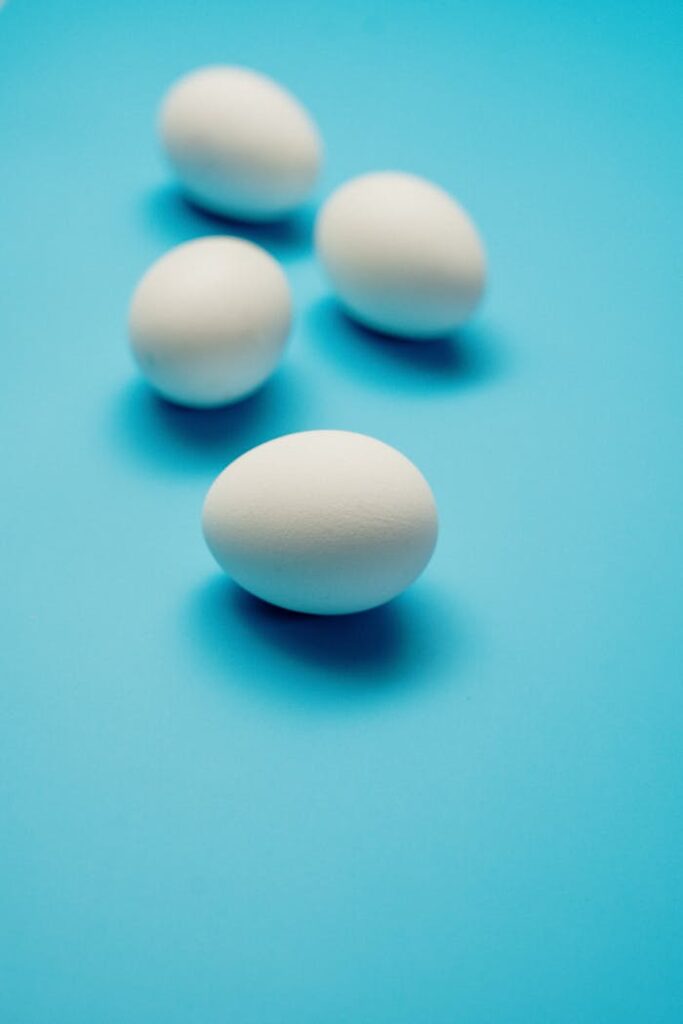 Four white eggs arranged on a bright blue surface, creating a minimalist and clean look.